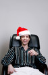 Foto: Businessman with christmas hat sitting on the chair laughing Businessman with christmas hat sitting on the chair laughing