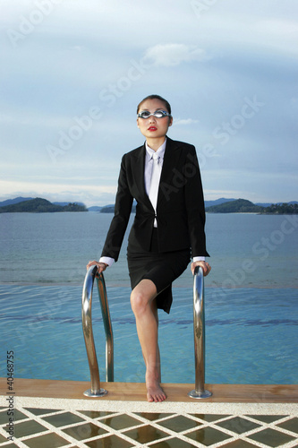 Photo: Businesswoman in goggles climbing out from the swimming pool Businesswoman in goggles climbing out from the swimming pool