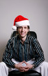 Foto: Businessman with christmas hat sitting on the chair smiling Businessman with christmas hat sitting on the chair smiling