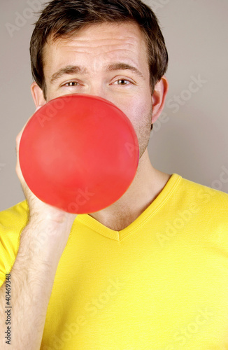Photo: Man blowing a red balloon Man blowing a red balloon