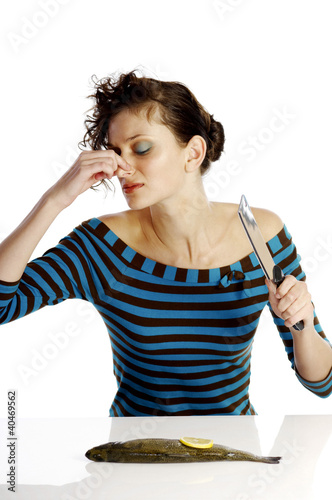 Photo: Woman pinching her nose while cutting a fish Woman pinching her nose while cutting a fish