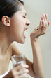 Woman eating pills while holding a glass of water