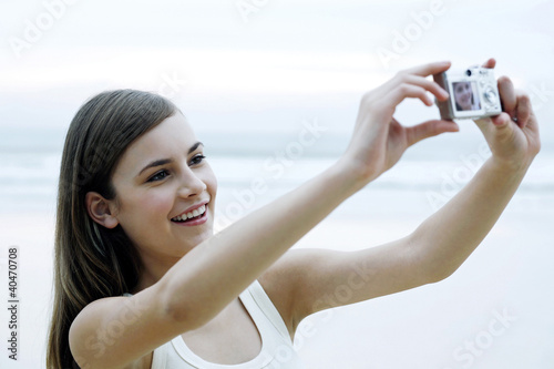 Photo: Woman taking her own picture with a digital camera Woman taking her own picture with a digital camera
