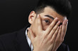 Businessman covering his face, peeping in between his fingers