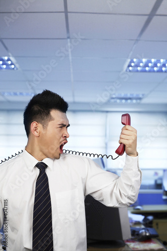Foto: Businessman shouting into a telephone receiver Businessman shouting into a telephone receiver