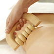 Hand using a wooden massager on woman's back
