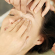 Hand using thread to remove facial hair from woman's face