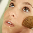 Hand applying powder foundation on woman's cheek