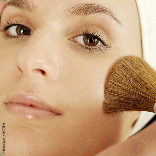 Photo: Hand applying powder foundation on woman's cheek Hand applying powder foundation on woman's cheek