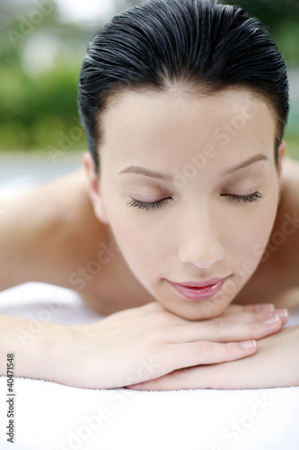 Photo: Woman lying forward on massage table with her eyes closed Woman lying forward on massage table with her eyes closed