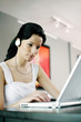 Woman listening to music on the headphones while using laptop
