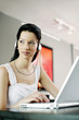 Woman listening to music on the headphones while using laptop