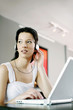 Woman listening to music on the headphones while using laptop
