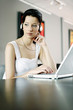 Woman listening to music on the headphones while using laptop
