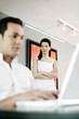 Man using laptop with his girlfriend standing in the background