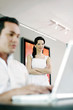 Man using laptop with his girlfriend standing in the background