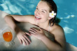 Woman in the swimming pool with a glass of orange juice by the pool side