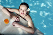 Woman in the swimming pool with a glass of orange juice by the pool side