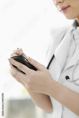 Photo: Female doctor using palmtop Female doctor using palmtop