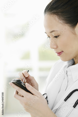 Photo: Female doctor using palmtop Female doctor using palmtop