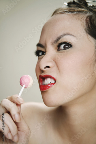 Photo: An angry young adult holding a lollipop An angry young adult holding a lollipop