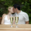 Two glasses of champagne with couple kissing in the background
