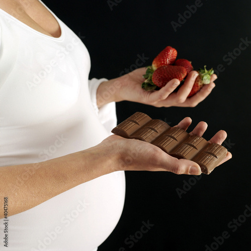 Photo: Pregnant woman with chocolate bar and strawberries Pregnant woman with chocolate bar and strawberries