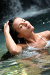 Beautiful woman enjoying bathing near natural waterfall