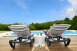 Back view of people relaxing on pool deck chairs