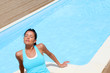 Brunette girl in fitness outfit relaxing by the pool