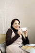 Woman holding a cup of coffee with magazine on her lap