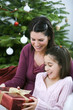 Little girl receiving a Christmas present from her mother