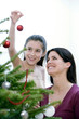 Mother and daughter decorating the Christmas tree 