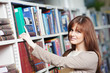 young adult student selecting book in library