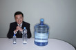 Businessman smiling at the camera with three water bottles on the table