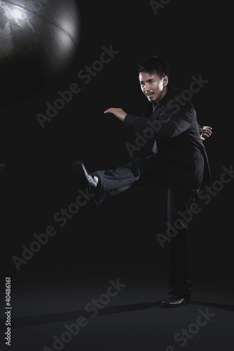 Photo: Businessman kicking globe Businessman kicking globe