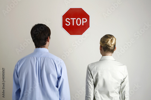 Photo: Businessman and businesswoman looking at a 'Stop' sign Businessman and businesswoman looking at a 'Stop' sign