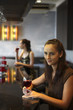Woman holding a wine glass smiling with another woman drinking wine in the background