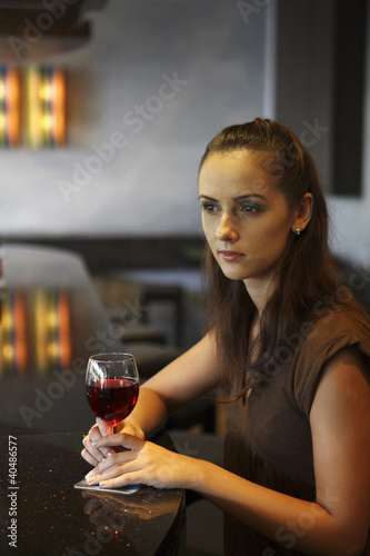 Foto: Woman holding a wine glass, looking away Woman holding a wine glass, looking away