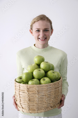 Photo: Woman with a basket of green apples Woman with a basket of green apples