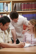 Two men and a woman studying in the library