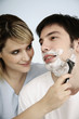 Woman shaving man's face