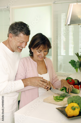 Photo: Man guiding woman in cutting vegetable Man guiding woman in cutting vegetable