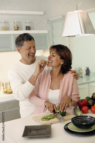 Photo: Woman cutting vegetable, man feeding woman Woman cutting vegetable, man feeding woman