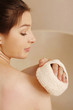 Woman cleaning body with bath sponge