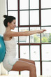 Woman pressing fitness ball against the wall, arms stretching forward