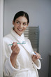 Woman in bathrobe holding toothpaste and toothbrush