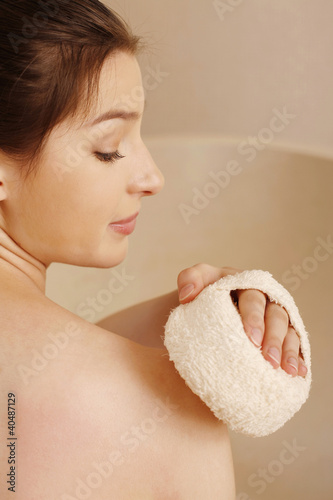 Foto: Woman cleaning body with bath sponge Woman cleaning body with bath sponge