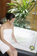 Woman sitting on the edge of bathtub testing the water