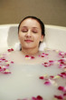 Woman relaxing in bathtub with flower petals